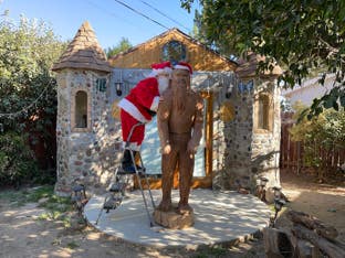 Casey McCaughn dressed up as Santa with her 8-foot sculpture of bigfoot